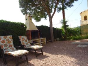 a backyard with two chairs and a brick oven at Casa Mediterráneo in La Marina