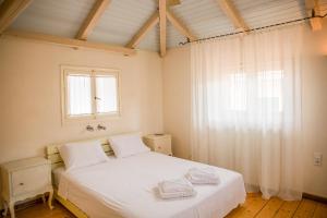 a bedroom with a white bed and a window at Lefkada Town Traditional House / Cozy Yard in Lefkada Town
