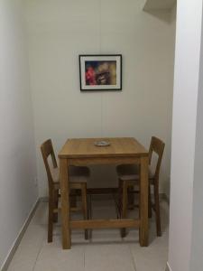 einem Holztisch mit zwei Stühlen und einem Bild an der Wand in der Unterkunft Le Studio du Château in Auriac-sur-Vendinelle