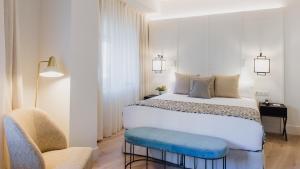 a bedroom with a large white bed and a chair at Molina Lario in Málaga