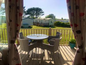 a patio with a table and chairs on a deck at B47 Caravan Seven Bays in Padstow