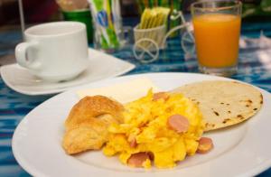 a plate of breakfast food on a table with orange juice at Hotel Bolivariana Plaza Medellin in Medellín