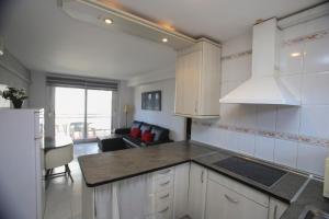 a kitchen with white cabinets and a living room at DIFFERENTFLATS Dms in La Pineda
