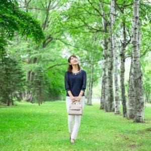 a woman walking in a park with a purse at Super Hotel Lohas Kumamoto Natural Hot Springs in Kumamoto