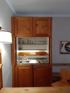 a kitchen with a sink and wooden cabinets at VILLAGGIO TURISTICO PLONER in Dobbiaco