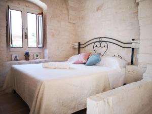 1 dormitorio con 1 cama con sábanas blancas y almohadas azules en Trulli stett, en Cisternino