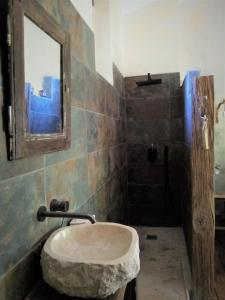 La salle de bains est pourvue d'un lavabo en pierre et d'un miroir. dans l'établissement Maison d'hôtes Ainsi Soie t-il, à Combovin