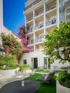 a patio with a table and chairs in front of a building at Hotel Molière in Cannes +31 photos