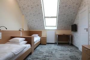 a room with two beds and a window and a tv at Motelik Grosar Jasło in Jasło