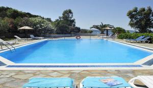 a large swimming pool with two chairs and a pool at Kassiopi Bay in Kassiopi