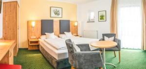 a hotel room with a bed and a table and chairs at Hotel Steffl Garni inkl Chiemgau Karte in Ruhpolding