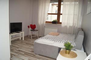 um pequeno quarto com uma cama e uma televisão em Red Apartament em Lódź