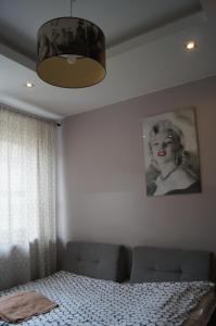Un dormitorio con una cama y una foto de una mujer en Red Apartament, en Łódź