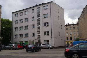 um grande edifício branco com carros estacionados num parque de estacionamento em Red Apartament em Łódź