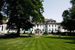ein großes weißes Haus mit einem großen Rasenhof in der Unterkunft Schlosshotel Bad Neustadt in Bad Neustadt an der Saale