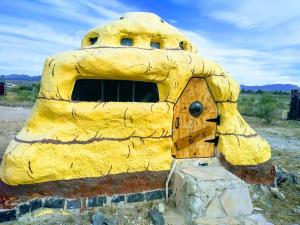 a large yellow structure with a door in the desert at La loma del chivo Llc Stone Cottage alternative building in Marathon
