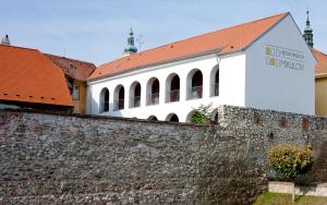 a white building with a red roof behind a wall at Městský penzion Mikulov in Mikulov