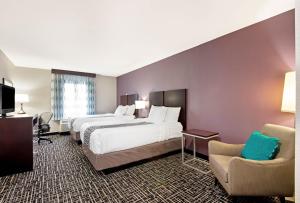 a hotel room with two beds and a chair at La Quinta by Wyndham New Cumberland - Harrisburg in New Cumberland