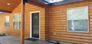 a wooden house with a black door and two windows at Eagle Cap Chalets in Joseph