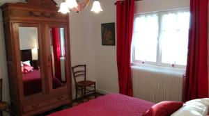 1 dormitorio con espejo y tocador con cortinas rojas en Gite de la Haute Verdière, en La Neuville-du-Bosc