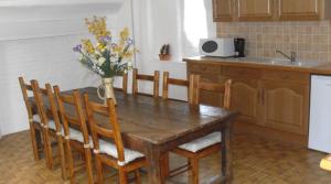 una cocina con una mesa de madera y un jarrón de flores en Gite de la Haute Verdière, en La Neuville-du-Bosc