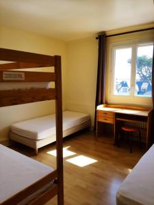 een slaapkamer met een stapelbed, een bureau en een raam bij Home des Pins SARL in Saint-Pierre-Quiberon