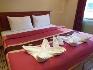 a bed with two pairs of shoes on it at Chaiyapoon Inn in Pattaya Central