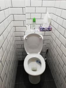 een badkamer met een toilet in een witte betegelde muur bij Rusne apartment in Rusnė