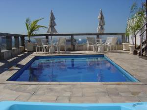 a swimming pool on a patio with chairs and umbrellas at Augusto's Copacabana Hotel in Rio de Janeiro