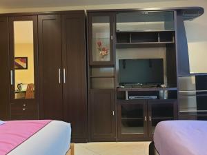 a bedroom with a television and wooden cabinets at Chaiyapoon Inn in Pattaya Central