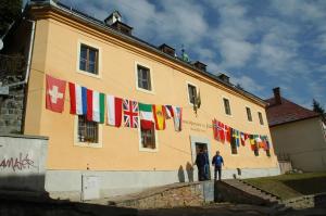 un grupo de banderas están colgando fuera de un edificio en Hostel Skautský dom, en Banská Štiavnica