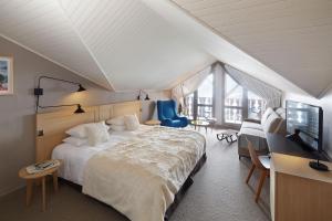 a bedroom with a bed and a desk and a television at Les Trois Vallées, a Beaumier hotel in Courchevel