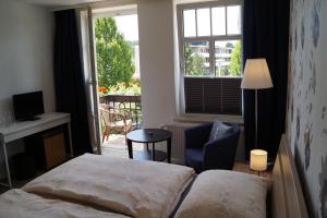 a bedroom with a bed and a chair and a window at Hotel Villa Undine in Grömitz