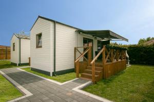 uma pequena casa branca com um portão de madeira e escadas em Domki z klimatem em Ustka