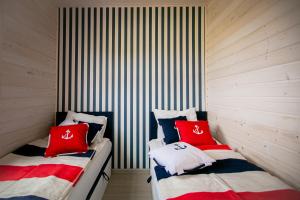 two beds in a room with red and white pillows at Domki z klimatem in Ustka
