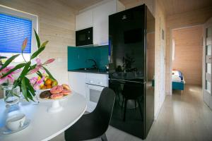 a kitchen with a white table and a black refrigerator at Domki z klimatem in Ustka