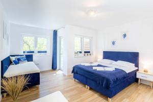 a bedroom with a blue bed and a couch at APARTAMENT 13B BLUE MARINE Poddąbie Basen Odkryty Brodziki Plac Zabaw in Poddąbie +20 photos