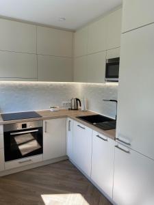 a kitchen with white cabinets and a stove top oven at DanGinta in Druskininkai