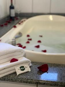 y baño con bañera llena de rosas rojas. en Real NOB Hotel en Orleães
