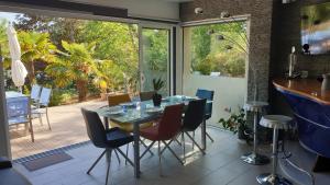 een eetkamer met een glazen tafel en stoelen bij Villa les Agapanthes avec piscine et SPA chauffée dans votre appartement in Hardelot-Plage