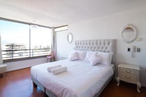 a bedroom with a white bed with a large window at Rose Gold - 1BR, Mountain View, Pool, Gym, Mall in Santiago