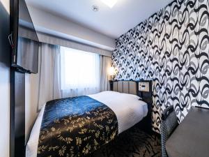 a hotel room with a bed and a patterned wall at APA Hotel Nambaminami Ebisucho Eki Shinsekai in Osaka