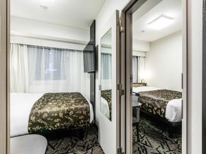 a hotel room with two beds and a mirror at APA Hotel Nambaminami Ebisucho Eki Shinsekai in Osaka