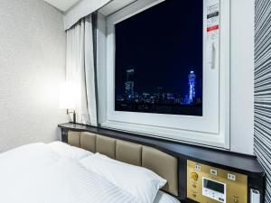a bedroom with a window with a view of a city at APA Hotel Nambaminami Ebisucho Eki Shinsekai in Osaka