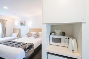 a hotel room with two beds and a microwave at Auckland Newmarket Motel in Auckland