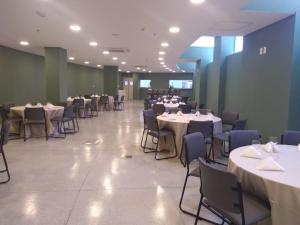 una sala da pranzo con tavoli e sedie con tavoli e sedie bianchi e sedie a sdraio di Barretos Thermas Park - CondoHotel a Barretos