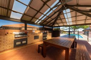 eine Außenküche mit einem Holztisch und einer Bank in der Unterkunft Geraldton's Ocean West Holiday Units & Short Stay Accommodation in Geraldton