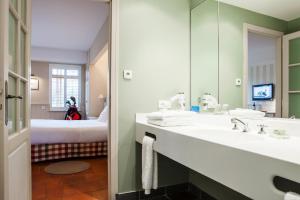 a bathroom with a sink and a mirror and a bed at Relais des Vigiers in Monestier