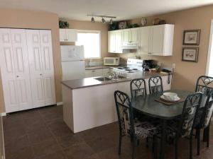 una cocina con mesa y sillas y una cocina con armarios blancos. en Paradise Canyon Golf Resort - Luxury Condo U401, en Lethbridge
