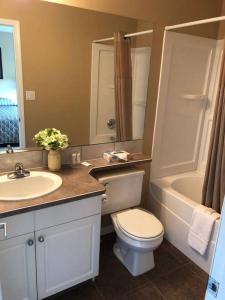 a bathroom with a sink and a toilet and a bath tub at Paradise Canyon Golf Resort - Luxury Condo U401 in Lethbridge